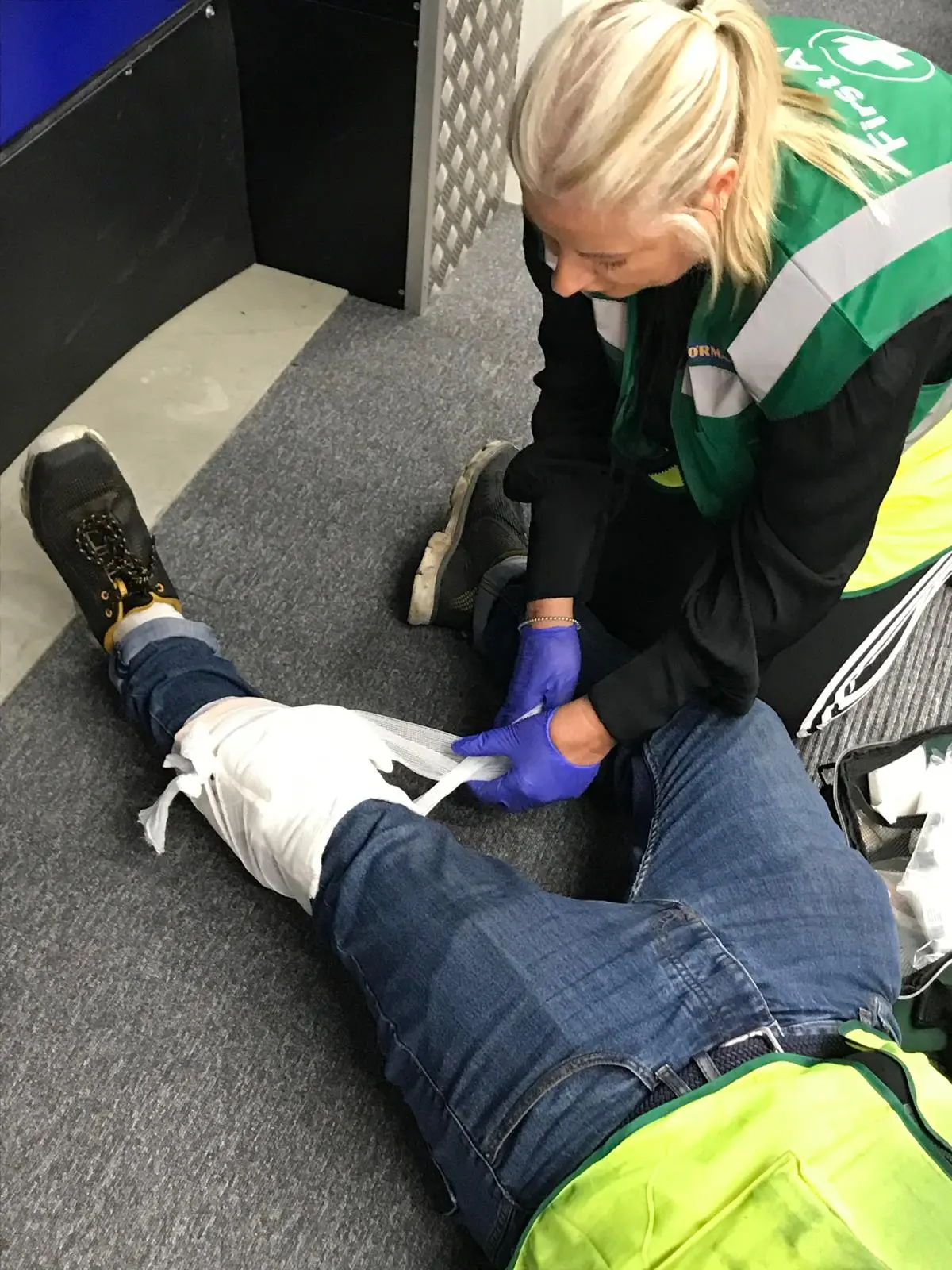 A learner applying a leg bandage during practical first aid training